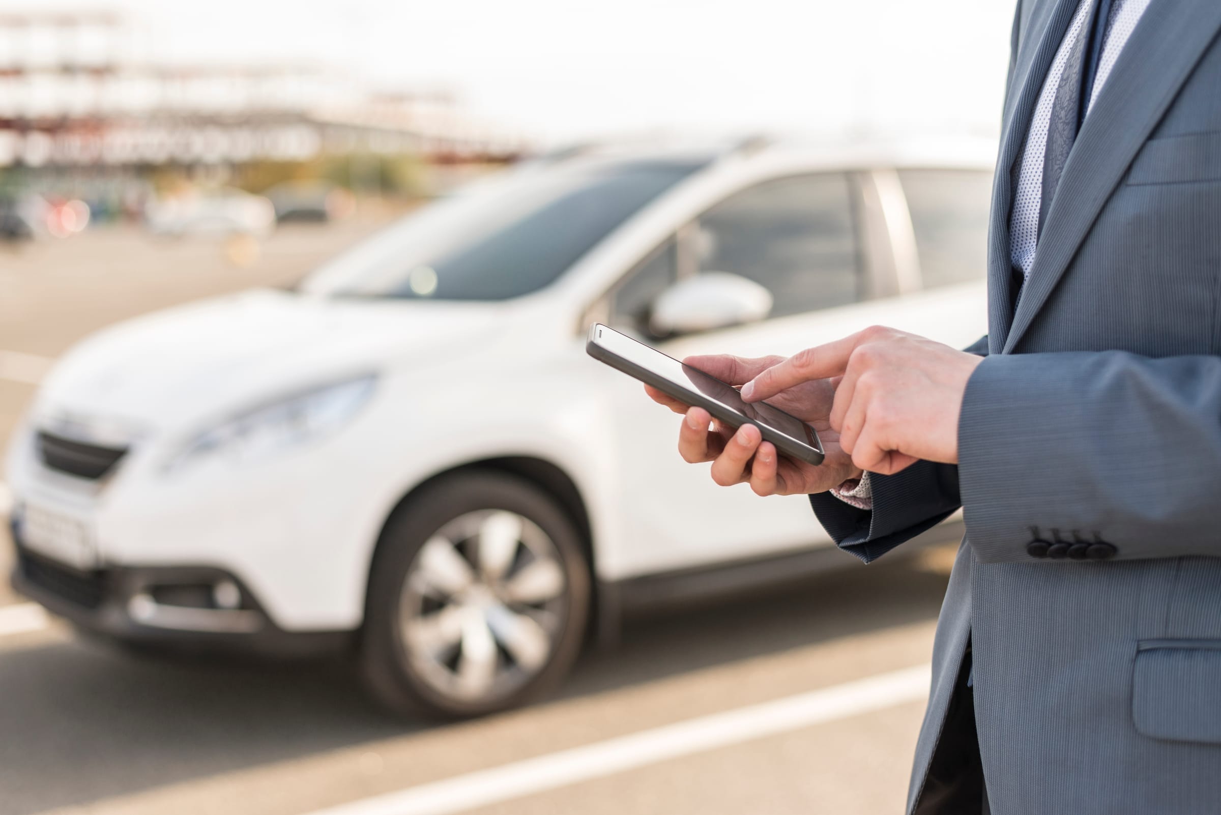 Cadre consultant son smartphone à côté de son véhicule de location